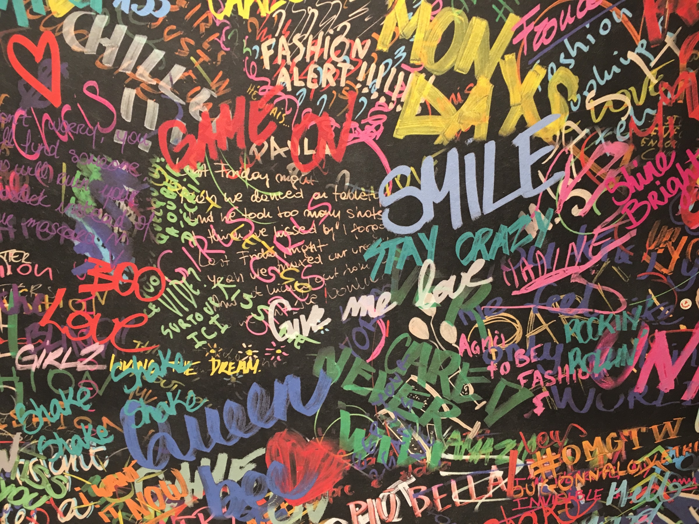 A black wall with different colourful English words written on it.