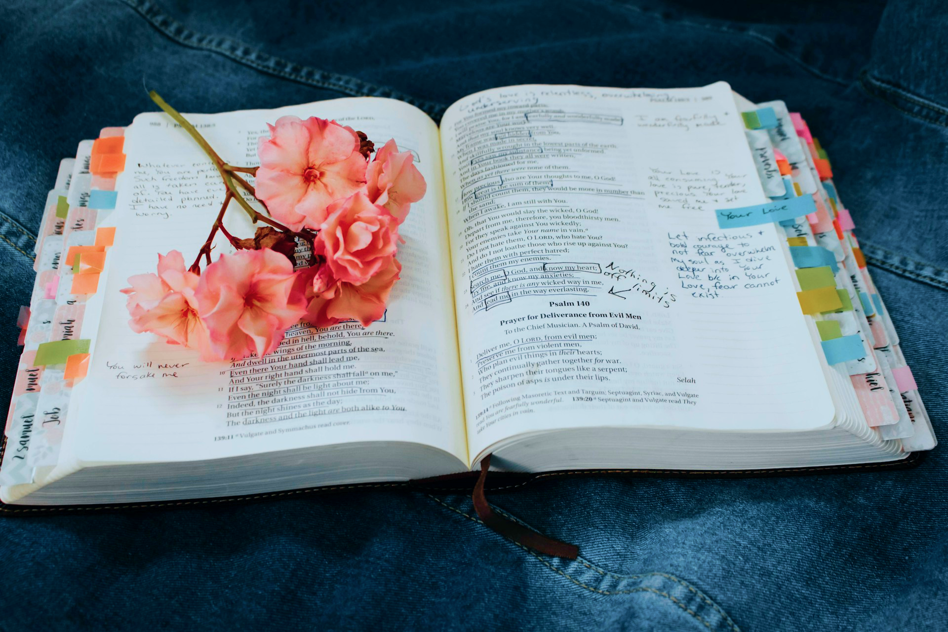 An open bible and a pink bunch of flowers on it.